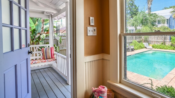A covered porch with a bench, a view of a backyard with a swimming pool, and a window with electrical outlets. - Historic Downtown Cottage with Private/Heated Pool! Walk to everything! (st. augustine)