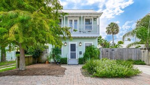 A two-story house with a front porch, a wooden fence, and a paved driveway. - Historic Downtown Cottage with Private/Heated Pool! Walk to everything! (st. augustine)