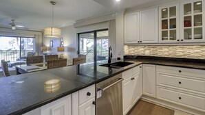 A modern kitchen with white cabinets, a black countertop, and a glass backsplash.