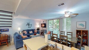 A living room with a sofa, a dining table, and a kitchen area with a sink. - Villa 212 3 bedrooms, 2 bathroom (Jekyll Island)