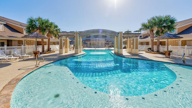 A swimming pool with a clear view of the surrounding buildings and a sunlit sky. - Poolside Coastal Retreat | Short Walk to the Beach (Corpus Christi)