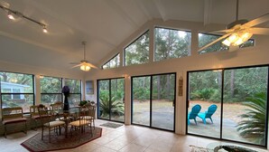 Una habitación amplia con comedor, ventanas grandes y ventilador de techo.