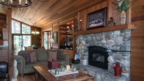 Una sala de estar acogedora con chimenea de piedra, paredes de madera y un sofá de cuero.