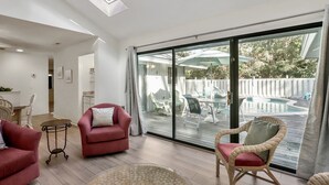Amplia sala de estar con un gran ventanal corredero que da a un patio exterior con piscina y mobiliario.