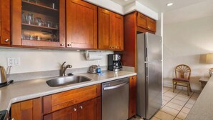 A kitchen with wooden cabinets, a stainless steel refrigerator, a dishwasher, and a coffee maker.