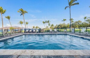 Ein Swimmingpool mit Liegestühlen und Palmen.