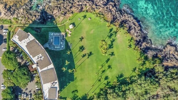An aerial view of a resort with a pool, a golf course, and a parking area.