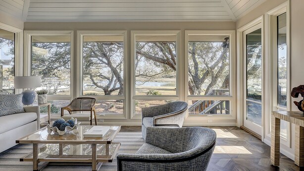 A sunroom with large windows, a sofa, two chairs, a coffee table, and a lamp. - 6 Portside- HEATED Community Pool. Fantastic views of South Beach Marina (Hilton Head Island)