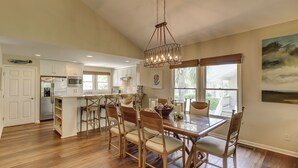 A spacious kitchen with a large island, wooden chairs, and a hanging light fixture. - 6 Portside- HEATED Community Pool. Fantastic views of South Beach Marina (Hilton Head Island)