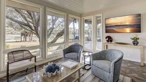 A spacious living room with large windows, a comfortable seating area, and a wall-mounted TV. - 6 Portside- HEATED Community Pool. Fantastic views of South Beach Marina (Hilton Head Island)