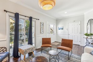 Relax in this stylish living area with a high ceiling, sliding glass door to a balcony, and comfortable seating for two.