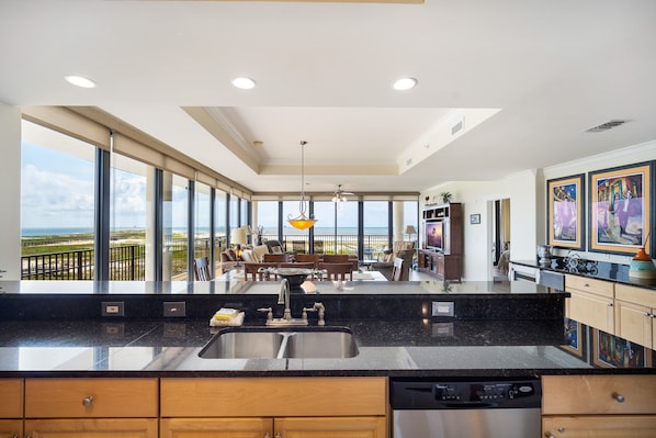 A modern kitchen with large windows, a dining area, and a view of the ocean.