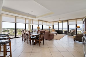 Enjoy expansive views of the surrounding landscape from the large windows in this room, which features a dining area, seating area, and balcony.