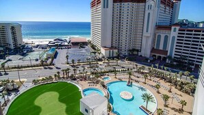 A hotel with a large pool, a golf course, and a view of the ocean.