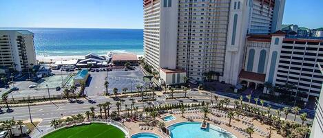 A hotel with a large pool, a golf course, and a view of the ocean.