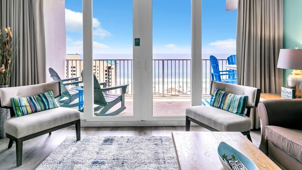 A room with a view of the beach, featuring two sofas, a coffee table, and a chair.
