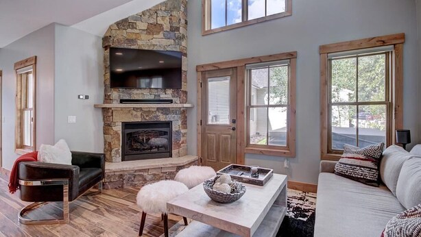 Un amplio salón con chimenea de piedra, un sofá cómodo y un ventanal que proporciona luz natural.