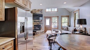 Una cocina moderna con refrigerador de acero inoxidable, armarios de madera y chimenea de piedra.