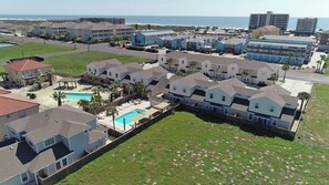 A residential area with houses, a swimming pool, and a view of the ocean.