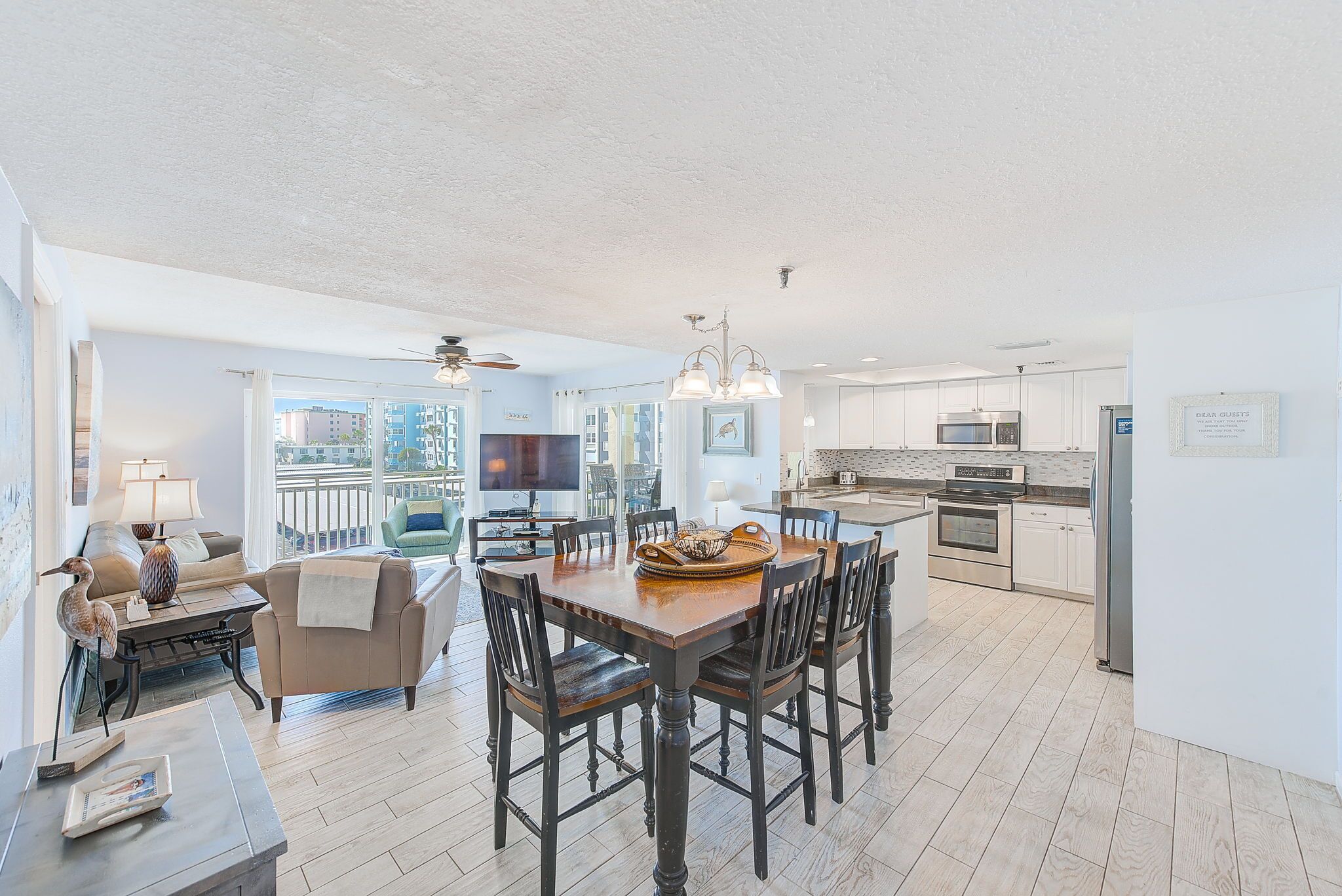 A spacious living area with a dining table, chairs, and a kitchen in the background.