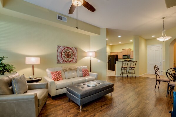 A living room with a sofa, ottoman, and a dining area with chairs and a table.