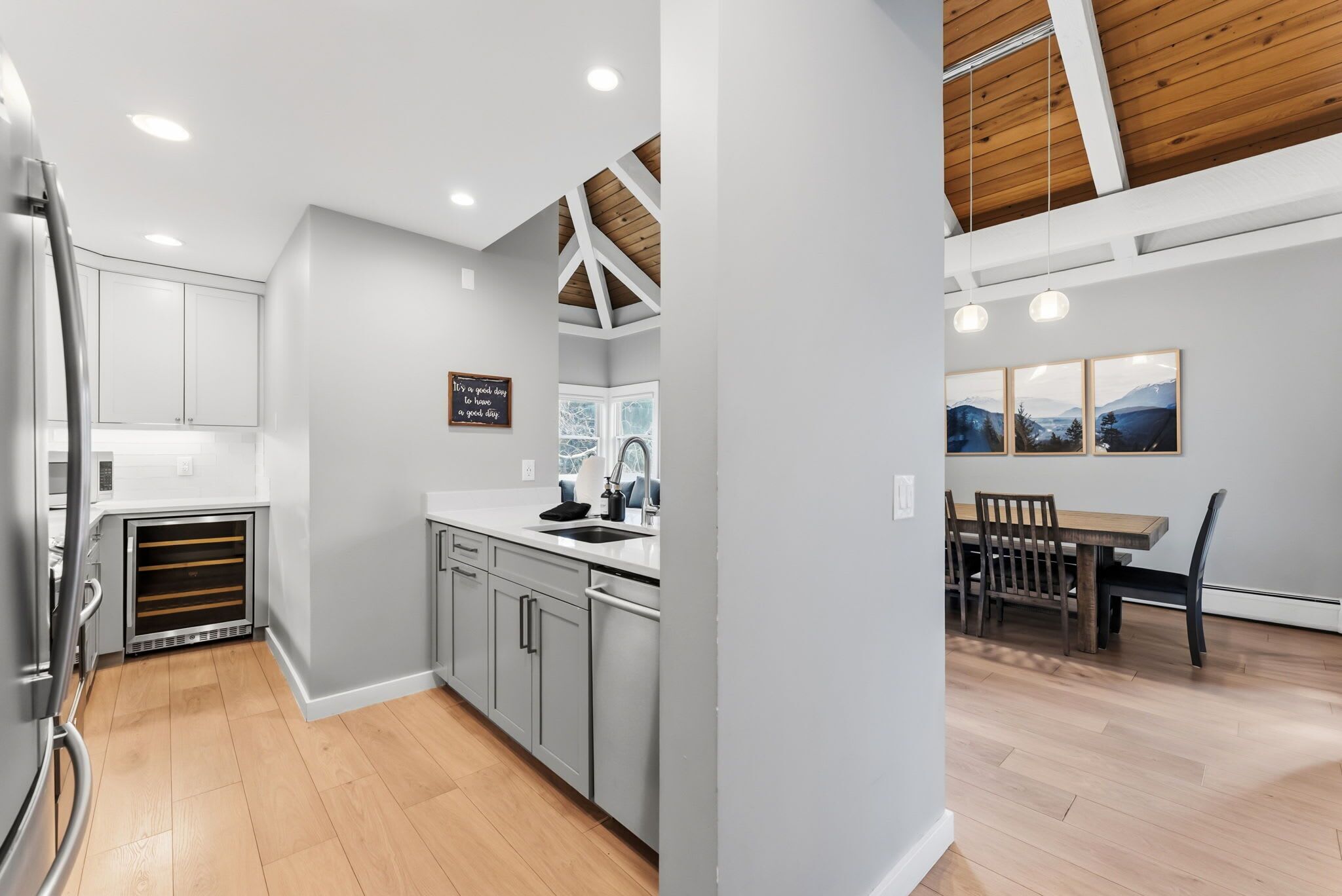 A modern kitchen with grey cabinets, a built-in oven, and a dining area with a wooden table and chairs.