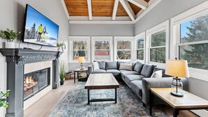 Una sala de estar moderna con chimenea, un sofá, una mesa de centro y ventanas amplias.