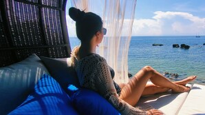 A person relaxing on a sun lounger with a view of the sea and rocks. - Clear View Resort (Koh Tao)
