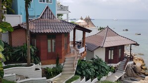 A coastal property with a wooden house, a thatched-roof structure, and a view of the sea. - Clear View Resort (Koh Tao)