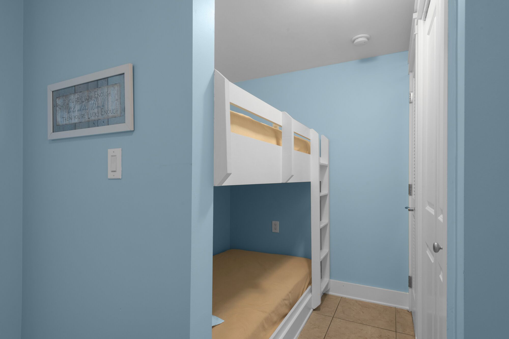 A bedroom with a bunk bed, a framed inspirational quote, and a door.