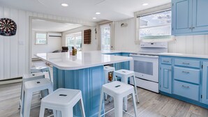 Eine moderne Küche mit blauen Schränken, einer weißen Arbeitsplatte und einer zentralen Kochinsel mit Barhocker.