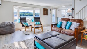 Ein Wohnzimmer mit Seeblick, zwei Ledersessel, ein braunes Ledersofa und ein Sitzsack.