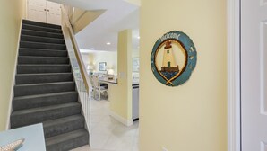 A staircase leading to a dining area with a wall-mounted welcome sign.