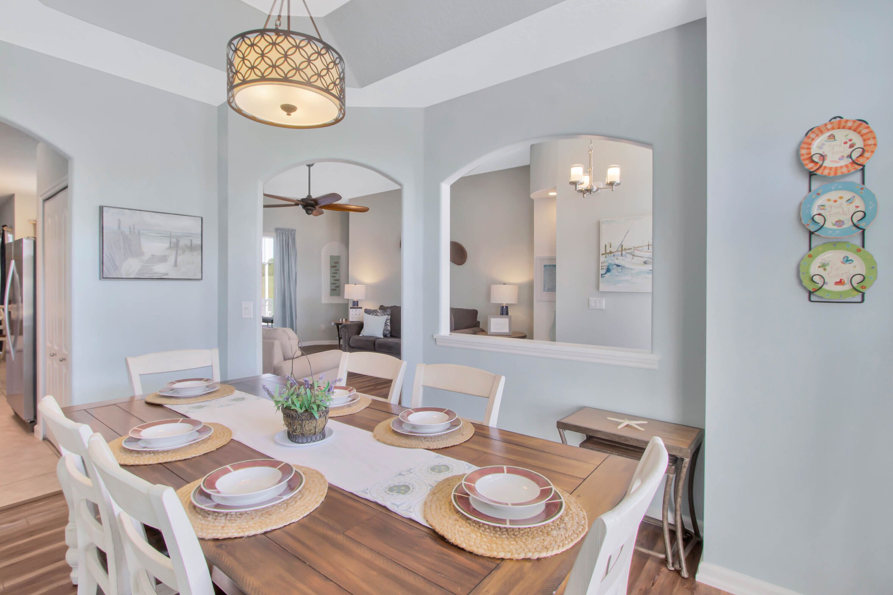 A dining area with a wooden table set for four, surrounded by white chairs.