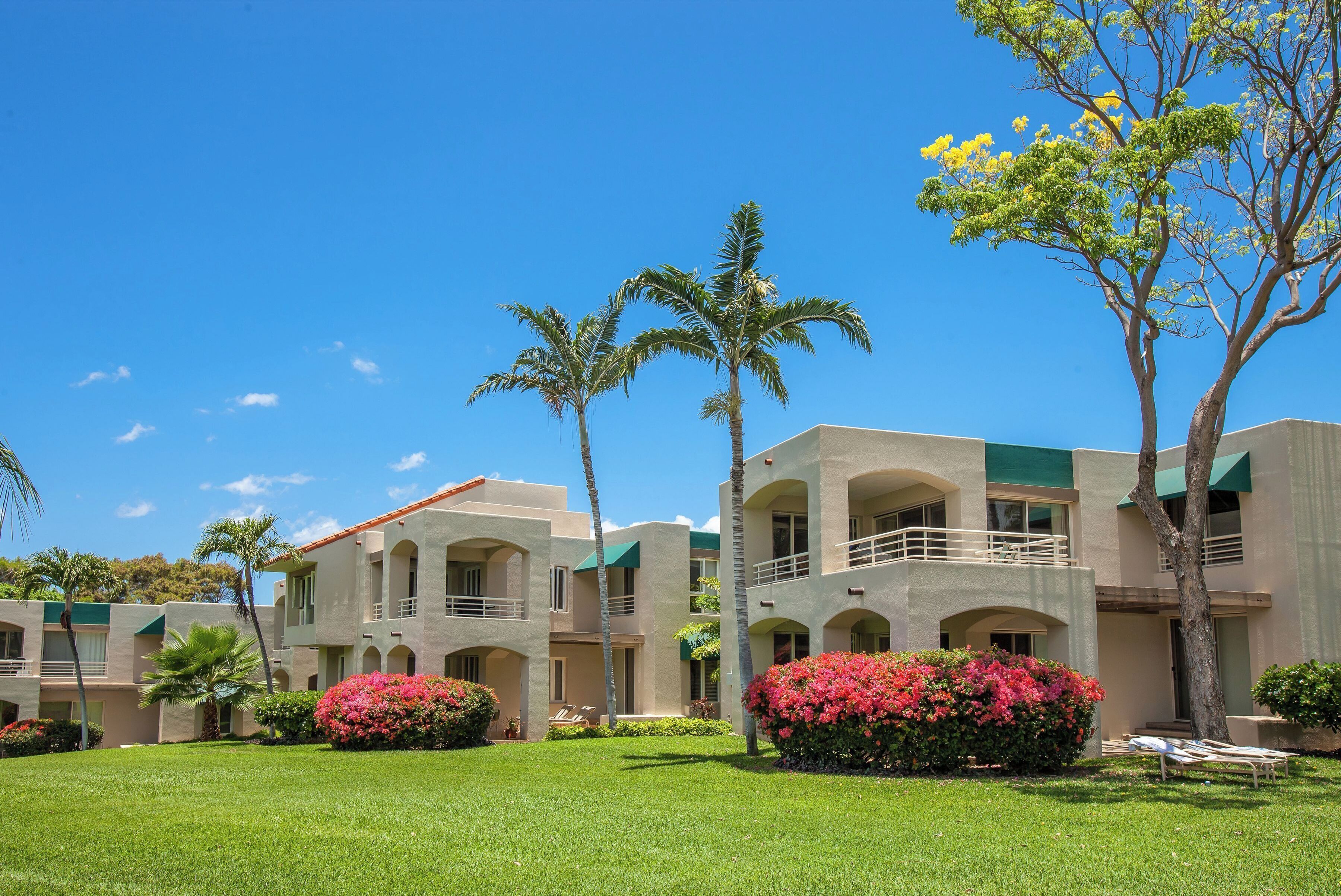 A hotel with multiple-story buildings, outdoor seating areas, and lush greenery.