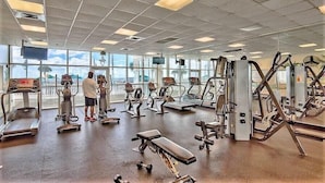 Une salle de sport équipée de tapis de course, de vélos elliptiques et de bancs de musculation.