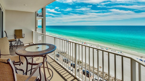 Un balcon donnant sur une plage, une table ronde et deux chaises.