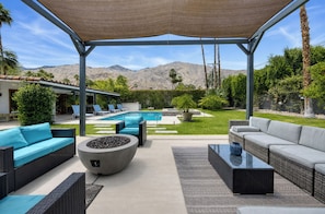 Un espace extérieur aménagé, abrité et doté d’une piscine, de chaises longues et d’une vue sur les montagnes.