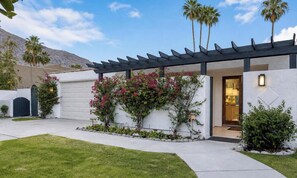 A modern house with a garage, a covered porch, and a well-maintained garden.