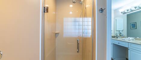 A glass-enclosed shower with a white bathtub, a white sink, and a mirror above the sink.