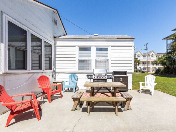 A patio with outdoor furniture, a grill, and a house in the background.