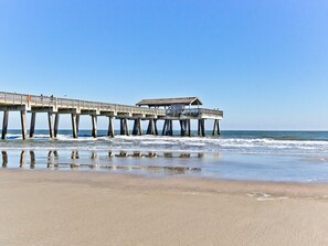 A pier extending into the ocean with a covered seating area.