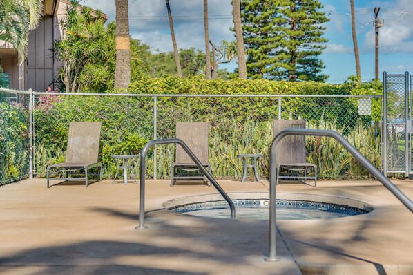 A swimming pool area with lounge chairs and a metal fence.