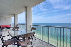 Un balcon avec une table et des chaises en verre, donnant sur une plage.