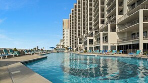 A swimming pool with lounge chairs and a high-rise building in the background.