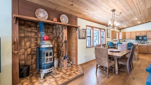 Eine rustikale Küche mit Holzofen, Esstisch, Stühlen und Holzausbau.