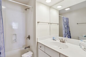 Ein modernes Badezimmer mit einem großen Spiegel, einer Dusche, einem Waschbecken und einer Toilette.