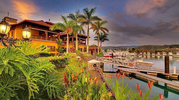A waterfront property with a dock, boats, and lush greenery. - Luxury Condo, Ocean & Golf Course View, access (Herradura)