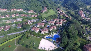 An aerial view of a residential area with houses, a golf course, and a swimming pool. - Luxury Condo, Ocean & Golf Course View, access (Herradura)