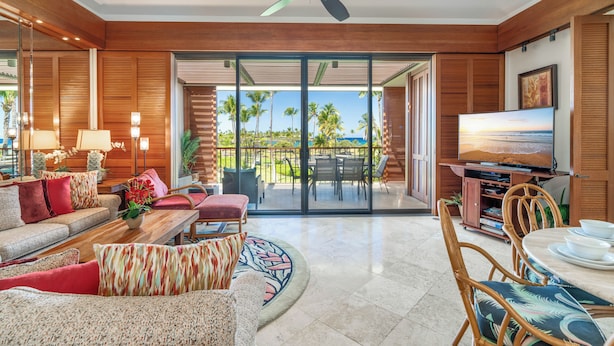 A spacious living room with a large TV, comfortable seating, and a view of the outdoors. - Gorgeous Oceanfront Terrace Condo - Near Beach Club! (Kamuela)